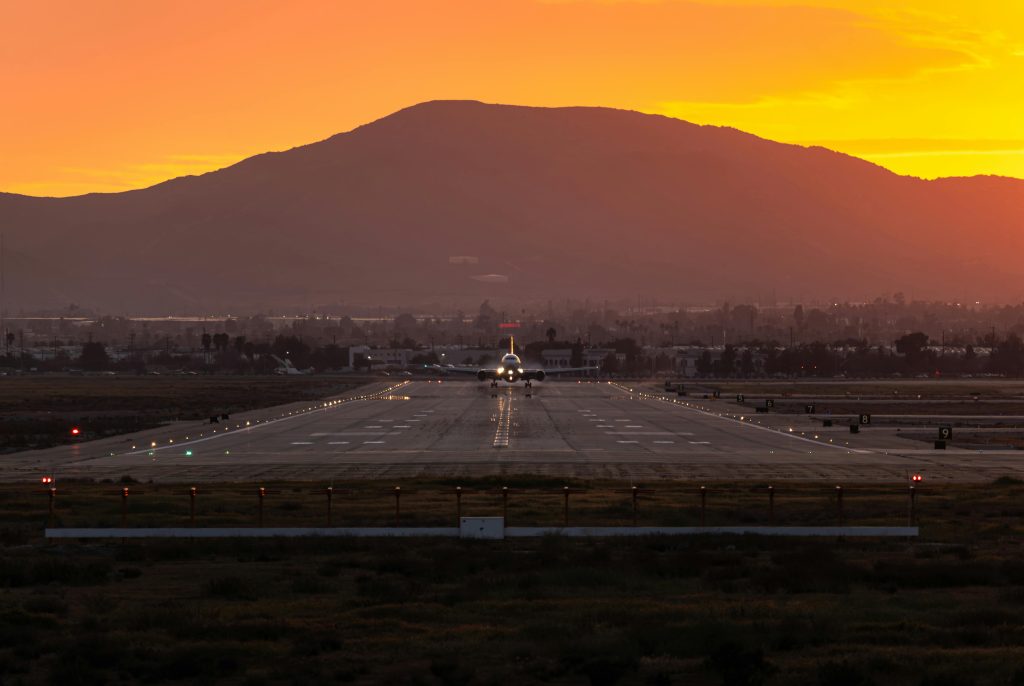 A stunning sunset view of an airplane landing at San Bernardino airport runway, California.